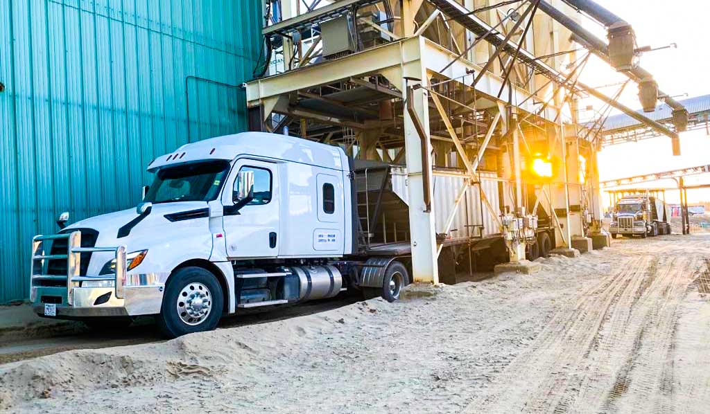 White truck at a loading facility at sunrise