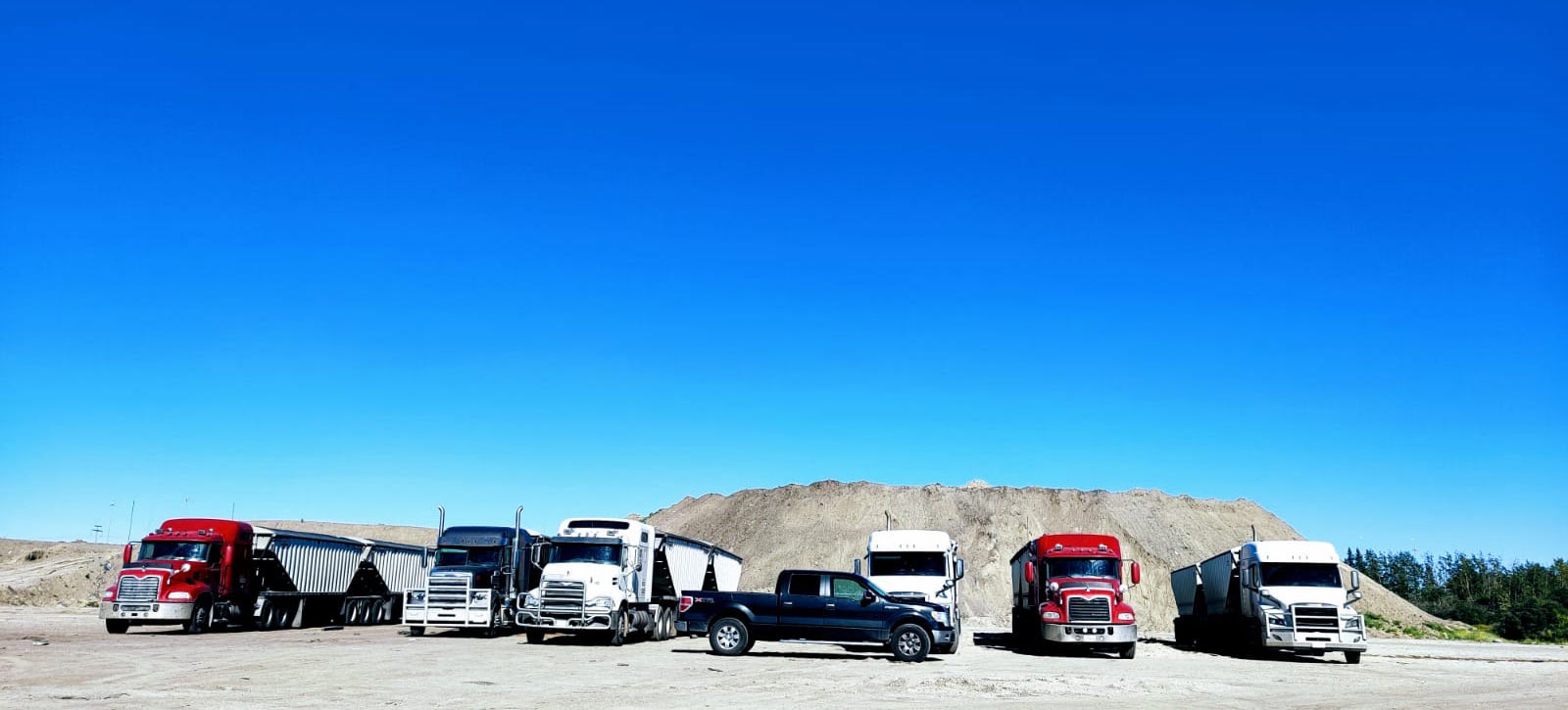 Six PB32 trucks lined up in front of a sand pile