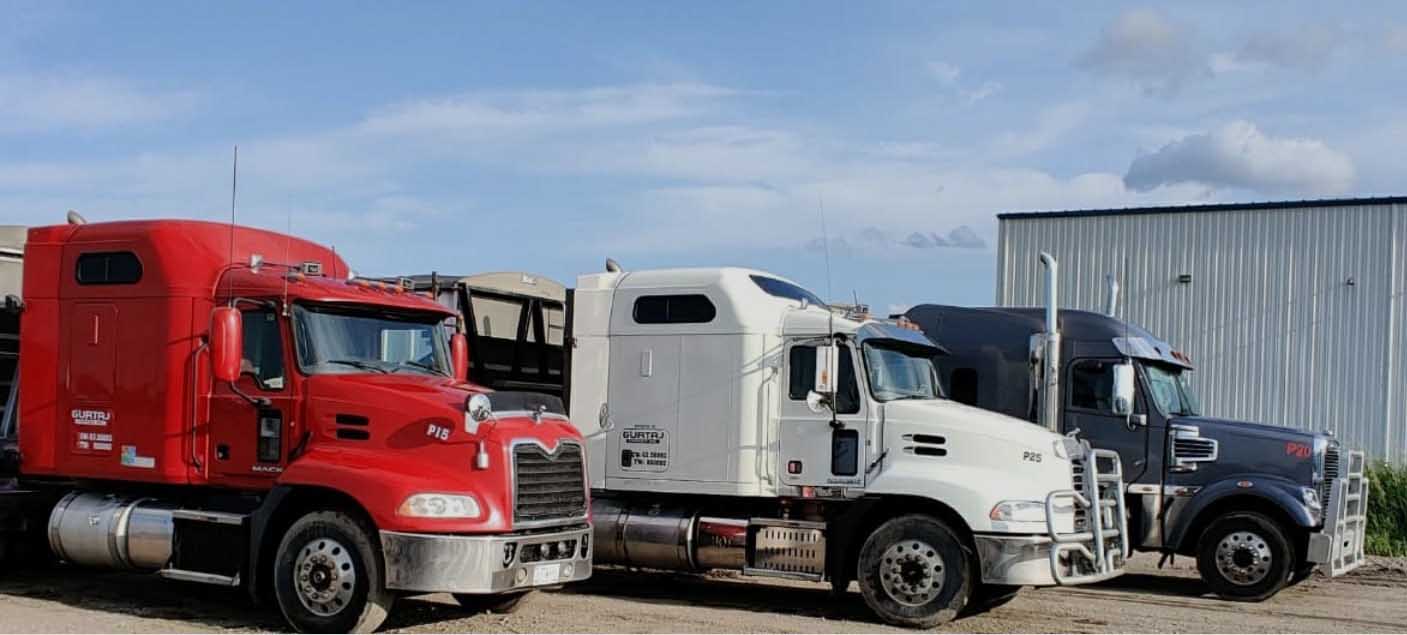 Red, white and black trucks beside a steel building